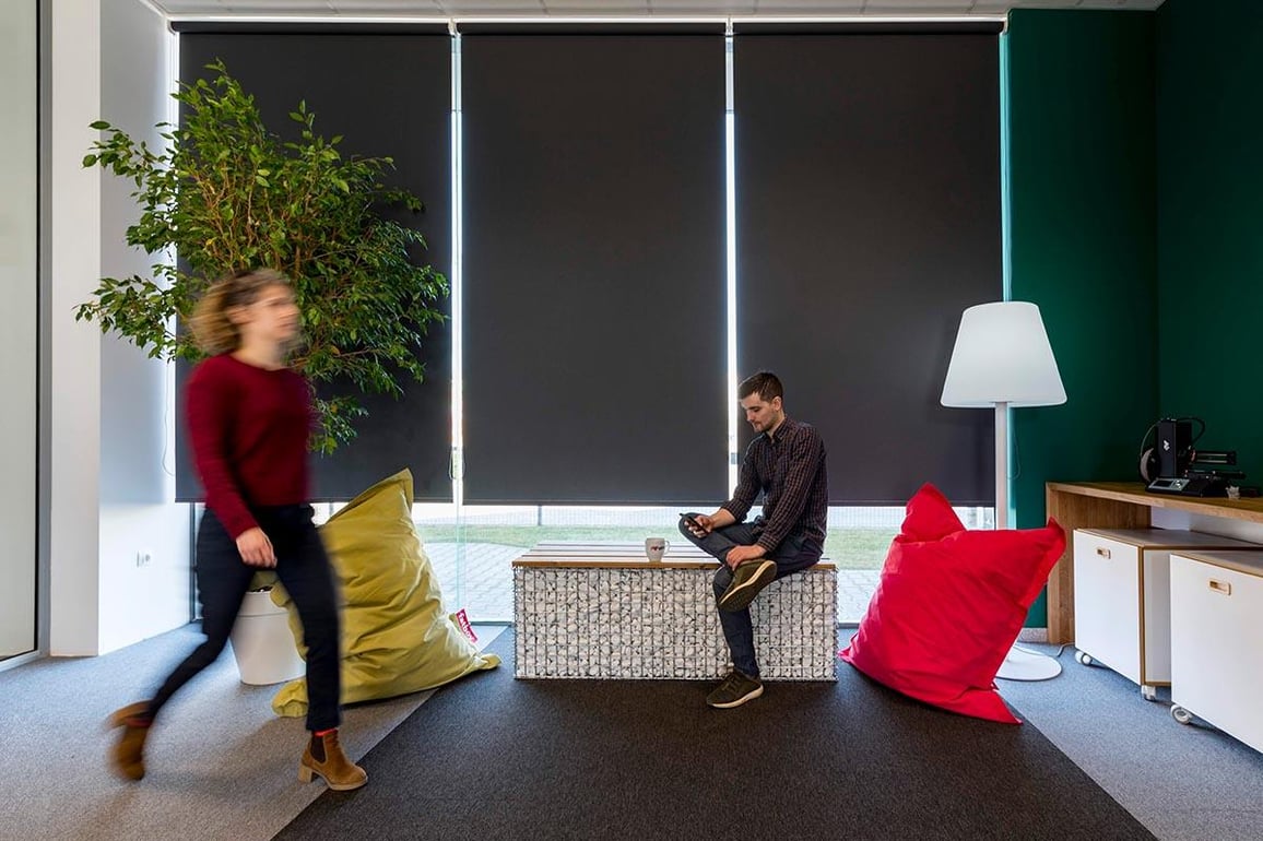 A young man with phone sitting on an original bench made of metal and stones in Aeco Space office.