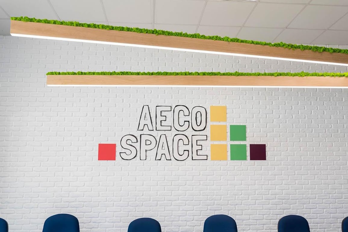 AECO Space logo on white brick wall and 6m long bespoke lamps covered with green moss.